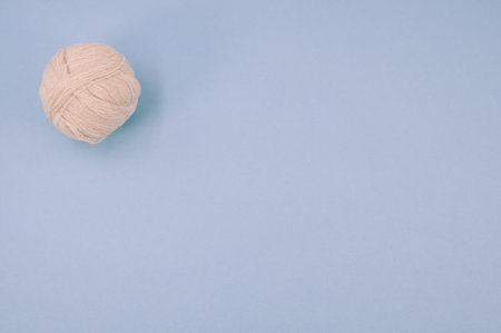 A vertical shot of isolated beige yarn on a blue background with text spaceの写真素材