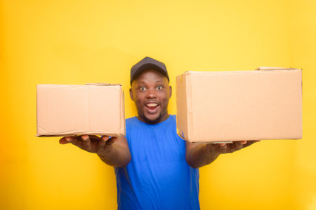 An African delivery or dispatch man carrying boxes and wearing a face capの写真素材