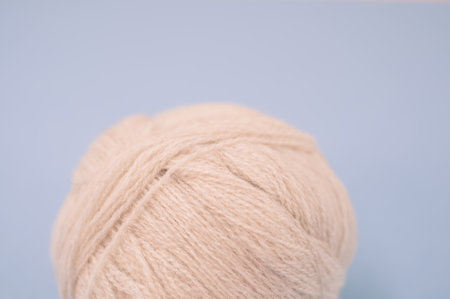 A vertical shot of isolated beige yarn on a blue background with text space