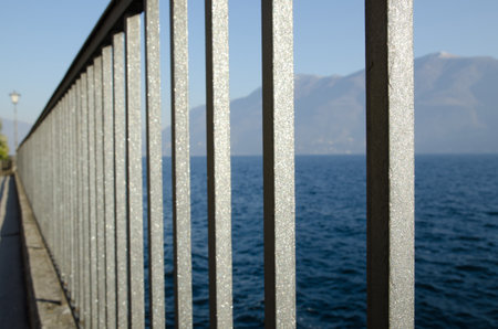 Banister and street lamp with lake and mountainsの写真素材