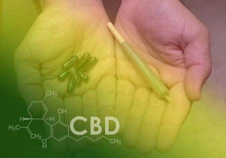 Close-up of a man's hands holding some pills in one and a cannabis joint in the other with the chemical formula of CBD. Concept of therapeutic cannabis, medical cannabis, legalization of cannabisの写真素材