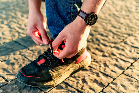 Close up shot of hands tying shoelaces sneaker on street.の写真素材