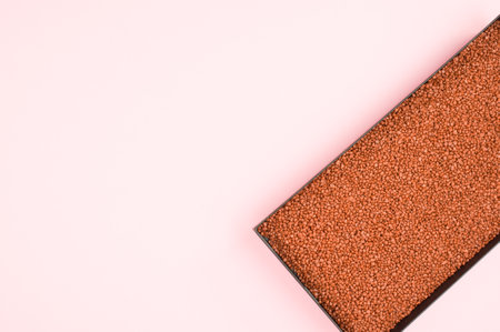 a metal box filled with terracotta color decorative sand on pink background with space for textの写真素材
