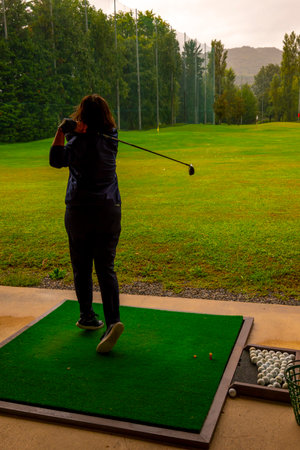 Golfer Training Her Golf Club Driver on Driving Range in a Rainy Day in Switzerland.の写真素材