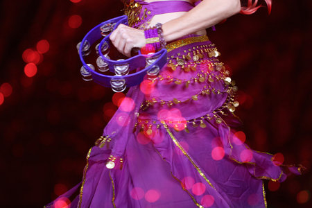 Belly Dancer wearing purple dance costume close up with colorful bokehの写真素材