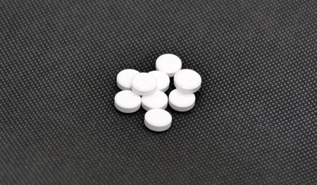 White tablets on black background photographed in a photo box