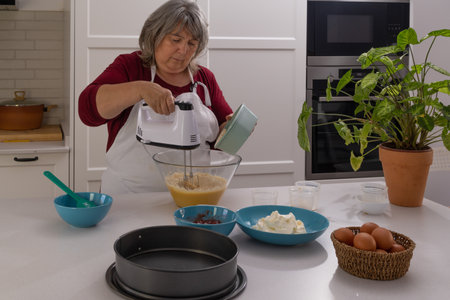 older woman with white hair making a strawberry cake in her home kitchen