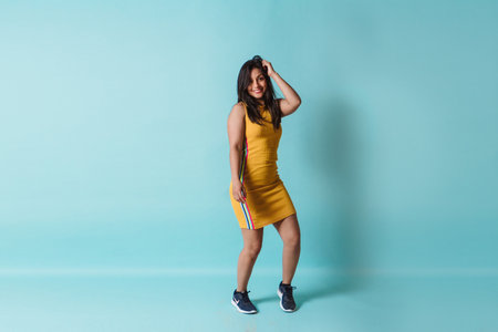 full length of a young happy latinx woman dancing looking at camera with copy space.の写真素材