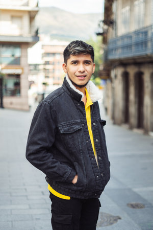 Latino man on the street with hands in jacket pocket looking at camera