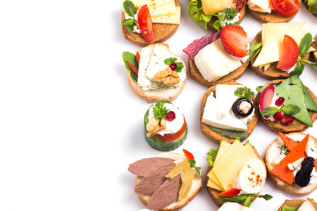 Different canapes with smoked salmon, cucumber cherry tomatoes and mozzarella served on a tableの写真素材