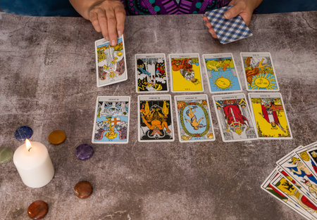 older white-haired woman reading tarot cards on a wooden table with candleの写真素材