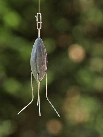 handmade fishing lead plumb bob hanging on green blur background