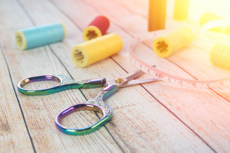 Sewing background. Accessories for needlework on wooden background. Spools of thread, scissors,...