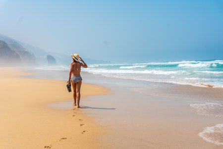 A young tourist with a hat walking alone on the Cofete beach of the Jandia natural park, Barlovento, south of Fuerteventura, Canary Islands. Spainの写真素材