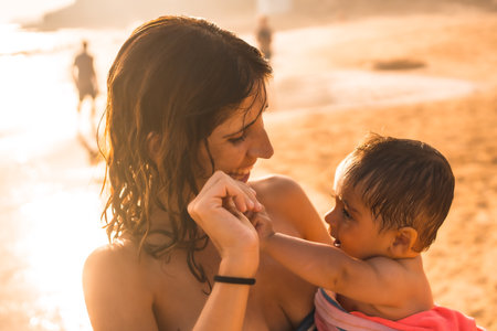 A young mother with her baby enjoying a sunset on a beach, Morro Jable, Municipality of Pajara south of Fuerteventura, Canary Islands. Spainの写真素材
