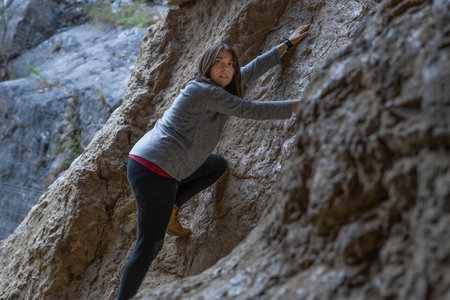young girl learning rock climbing in high mountain with blue sweater, black tights and boots.の写真素材