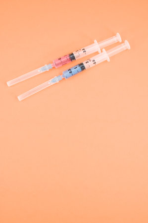 an isolated injection syringe on orange paper background with text spaceの写真素材