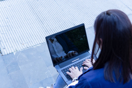 Unrecognizable Beautiful Caucasian businesswoman with laptop  sitting outside working in the streetの写真素材