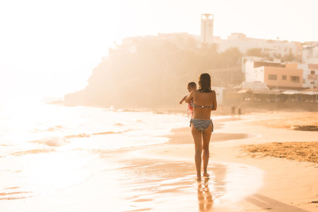 A young mother with her six-month-old baby at sunset on a beach, Morro Jable, Municipality of Pajara south of Fuerteventura, Canary Islands. Spainの写真素材