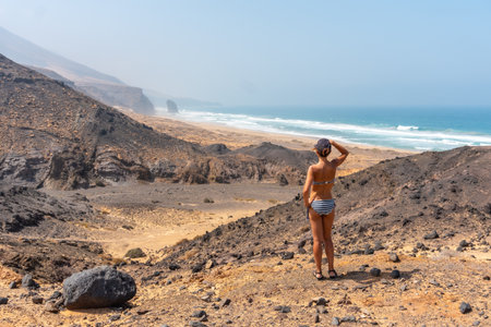 A young woman on a path of the wild beach Cofete of the natural park of Jandia, Barlovento coast, south of Fuerteventura, Canary Islands. Spainの写真素材