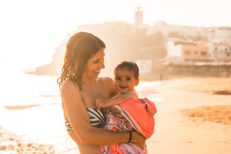 A young mother with her six-month-old baby enjoying a sunset on a beach, Morro Jable, Municipality of Pajara south of Fuerteventura, Canary Islands. Spainの写真素材