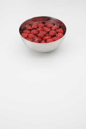 sweet tasty raspberries in a bowl filled with water on white background and copy spaceの写真素材