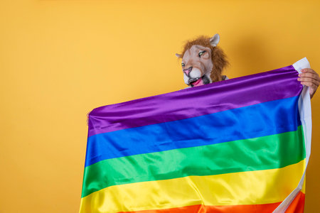 Person with lion mask showing a LGBTI flag. Concept of gender identity.の写真素材