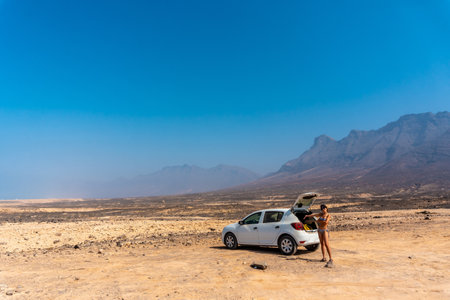 A young girl with the rental car on the Cofete beach of the Jandia natural park, Barlovento, south...