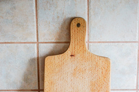Wooden cutting board against a tile wall