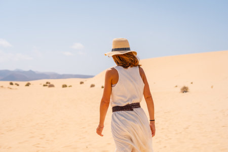 A young tourist wearing a hat walking along the sand on the beaches of the Corralejo Natural Park, Fuerteventura, Canary Islands. Spainの写真素材