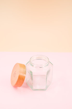 Empty glass jar with a wooden lid isolated on a pink background with copy spaceの写真素材