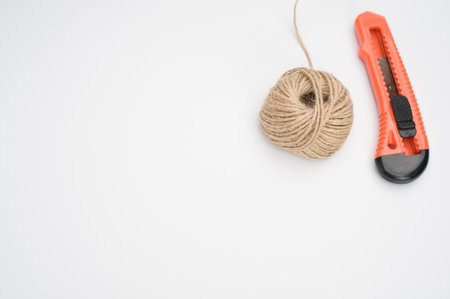A closeup of a stationary knife and a yarn ball isolated on a white backgroundの写真素材