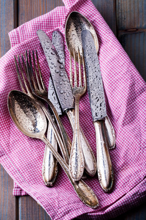 damp silver cutlery with kitchen towel on wooden background