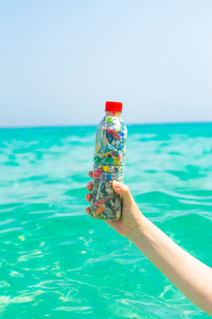 Bottle filled with microplastics collected from the sea with the sea in the background.の写真素材