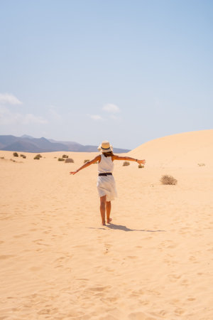 A young tourist wearing a hat walking through the dunes of the Corralejo Natural Park, Fuerteventura, Canary Islands. Spainの写真素材