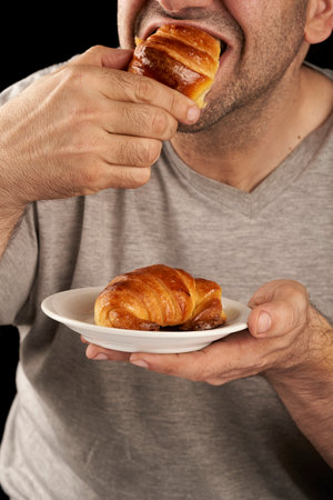 man eating sweet buttered croissantsの写真素材