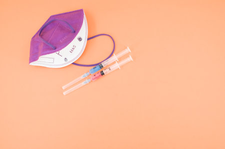Isolated respiratory mask with syringe on an orange paper background wit text space