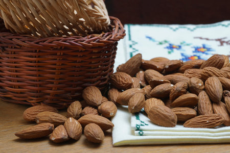several almonds scattered on table with tablecloth and a couple of basketsの写真素材