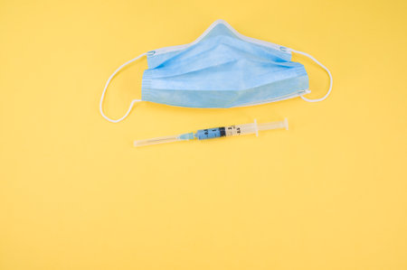 Isolated respiratory mask with syringe on a yellow paper background wit text spaceの写真素材