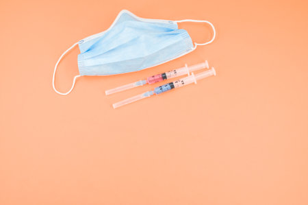 Isolated respiratory mask with syringe on an orange paper background wit text spaceの写真素材