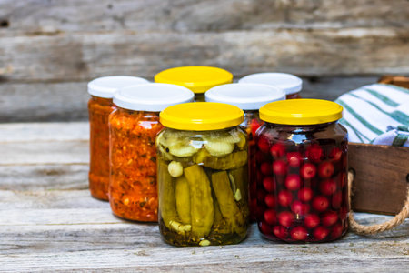 Jars with variety of canned vegetables and fruits, jars with zacusca. Preserved food concept in a...