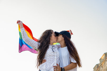 Couple lesbian woman with gay pride flag on the street