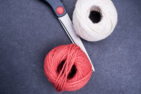multicolor decoration yarns with scissors on a dark stone background with copy spaceの写真素材