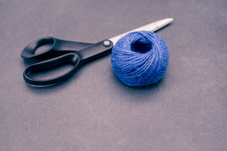multicolor decoration yarns with scissors on a dark stonebackground with copy spaceの写真素材