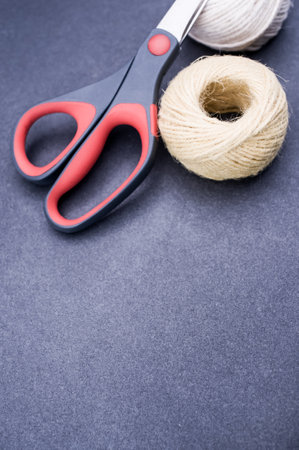 multicolor decoration yarns with scissors on a dark stone background with copy space