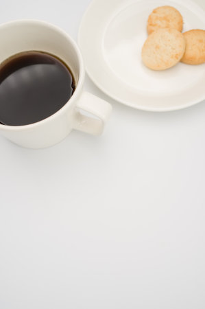 black coffee in a mug and plate with biscuits on a white background with copy spaceの写真素材