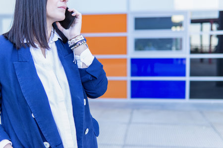 Unrecognizable Caucasian businesswoman talking on phone outside an office buildingの写真素材