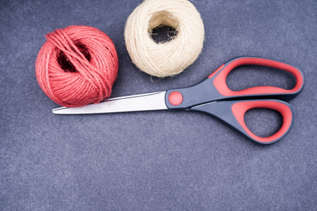 multicolor decoration yarns with scissors on a dark stone background with copy spaceの写真素材