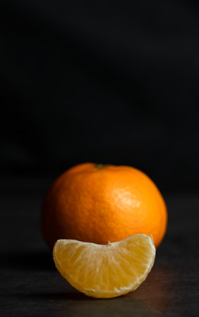 A mandarin and a piece of mandarin, black backgroundの写真素材