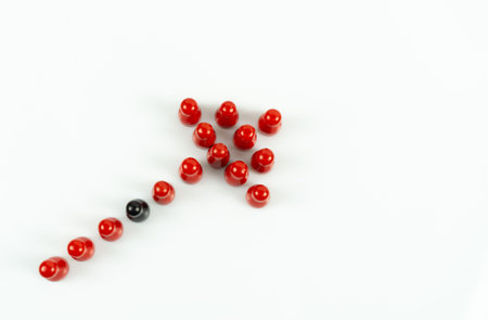 Many red meeple shaped like an arrow and one black meeple between, white background and copy spaceの写真素材
